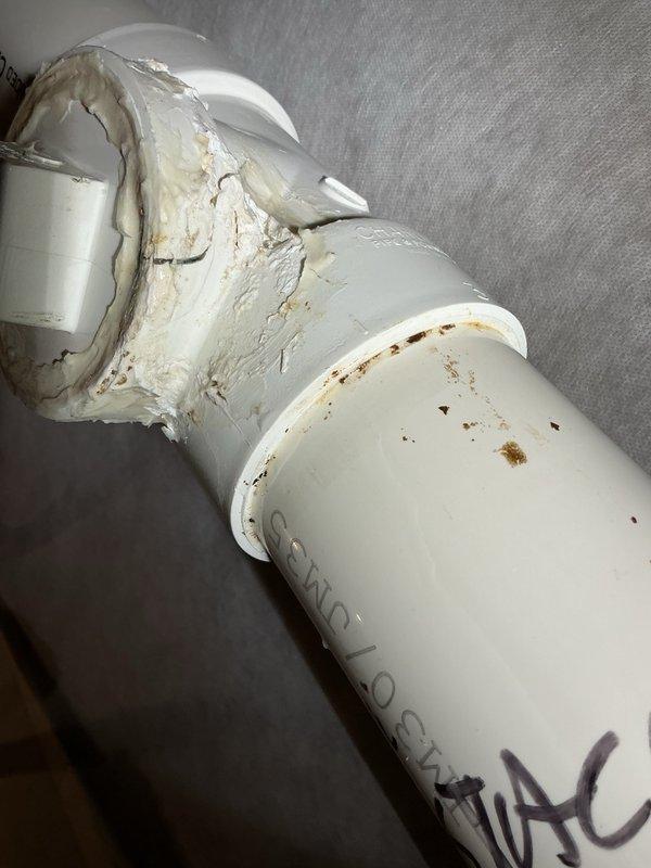 Responded to a water leak complaint originating from the upstairs bathroom with water pooling in the basement. Upon inspection, identified a cracked clean-out tee fitting on the basement drain pipe as the source of the leak. Cut out the damaged clean-out tee and installed a new replacement fitting to restore proper drainage function and eliminate the water intrusion. Documented the deteriorated condition of the original component, which showed significant cracking and surface degradation, and verified the new installation was secure and leak-free.