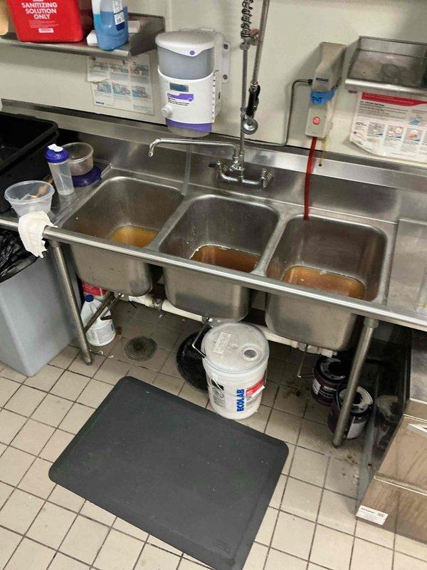Responded to a commercial kitchen drain backup affecting all three bays of a stainless steel triple-basin sink system. Upon arrival, found standing water and backup in all compartments with the issue isolated to the shared drain line; no other fixtures were affected. Cabled the kitchen sink drain to clear the obstruction and restore proper flow. Tested the repair by running water through all three basins, filling each compartment, and dumping multiple times to verify complete drainage and confirm the system was functioning properly. All sinks now draining freely with no signs of backup.