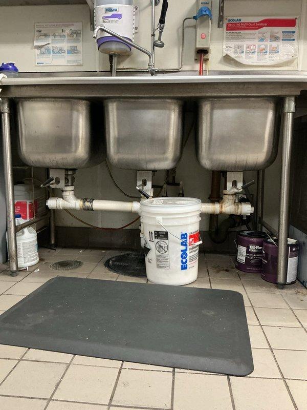 Responded to a commercial kitchen drain backup affecting all three bays of a stainless steel triple-basin sink system. Upon arrival, found standing water and backup in all compartments with the issue isolated to the shared drain line; no other fixtures were affected. Cabled the kitchen sink drain to clear the obstruction and restore proper flow. Tested the repair by running water through all three basins, filling each compartment, and dumping multiple times to verify complete drainage and confirm the system was functioning properly. All sinks now draining freely with no signs of backup.