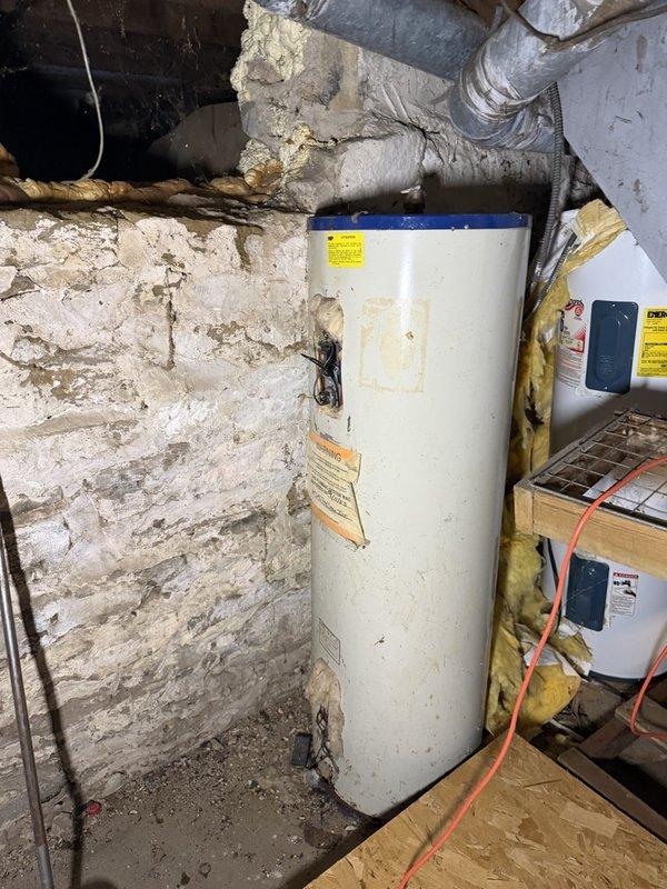 Responded to no hot water complaint on gas-fired tanked water heater. Upon arrival, diagnosed tripped thermostat as cause of system failure. Successfully reset thermostat and restored hot water operation. Unit identified as 21-year-old Richmond brand water heater with 6-year limited warranty on tank and parts, showing visible signs of age including exterior staining and wear. Provided customer with estimates for both repair options and full replacement of aging unit given its advanced age and condition.