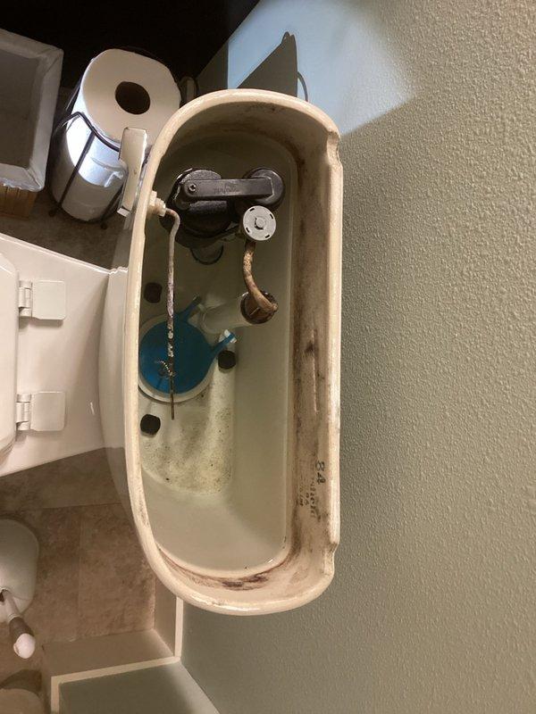 Completed recurring plumbing inspection of residential property, examining all accessible fixtures and components. Documented significant mineral buildup and corrosion inside toilet tank, including heavily rusted flush chain and interior staining indicating water quality concerns. Observed bathtub with substantial surface staining, rust discoloration along seam areas, and general accumulation of debris requiring attention. Provided estimates for recommended repairs and replacements based on inspection findings.