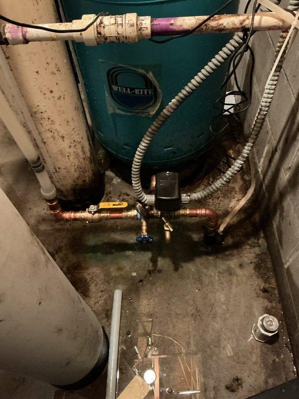 # Emergency Water Leak Repair - Well Tank System

Responded to emergency call for active water leak in basement utility area. Upon arrival, found significant flooding with water accumulation across concrete floor. Customer was unable to identify leak source or water shut-off location.

## Problem Identified

Conducted thorough inspection of plumbing system and identified failed adapter connection on Well-Rite pressure tank (Tank T). The broken adapter was causing uncontrolled water discharge, resulting in basement flooding with water levels reaching several inches deep.

## Work Performed

- Located and shut off water supply to isolate affected system
- Assessed extent of flooding and leak damage to utility room
- Removed failed adapter component from pressure tank
- Installed new replacement adapter on Tank T
- Reconnected all associated copper piping and fittings to pressure tank system
- Restored water supply and tested system for proper operation
- Verified all connections were sec