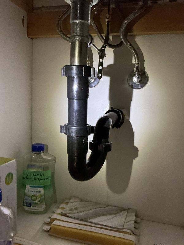 Completed biannual plumbing inspection including water heater tune-up and seasonal exterior faucet service. Inspected toilet tank flush mechanism components and noted mineral deposits and staining on interior tank walls requiring monitoring. Documented under-sink plumbing configuration with P-trap assembly and supply lines in proper working condition.