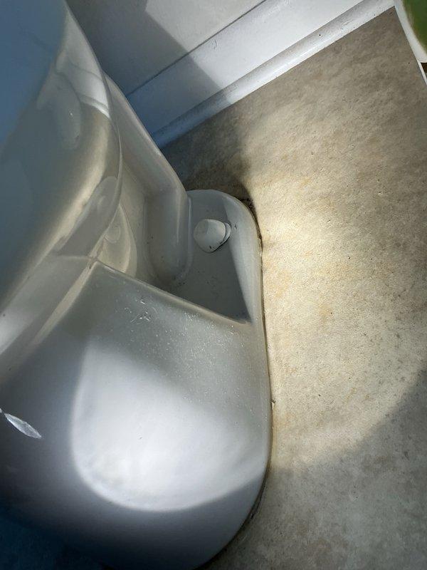 Responded to emergency call for toilet leaking through ceiling into kitchen below. Upon inspection, identified failed wax ring as source of leak. Removed toilet and assessed flange condition—cast iron flange found to be structurally sound with no replacement required at this time. Installed new wax ring, properly reset toilet to ensure proper seal, and applied caulking along front base for added stability. Advised property owner that future leak issues may necessitate flange replacement and subfloor repair due to age of existing components.