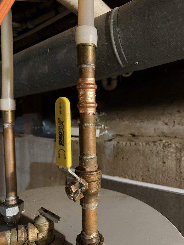 Returned to property to remove obsolete piercing valve from copper water line that previously supplied a humidifier. The piercing valve was successfully disconnected and removed from the vertical copper pipe assembly, completing the cleanup work following the previous day's installation. All connections were left secure and the plumbing system restored to proper working condition.