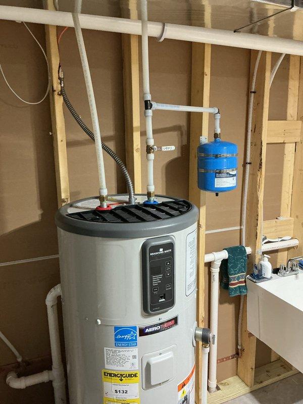 Installed a whole home carbon water filtration system with blue cap housing, mounting brackets, and white PVC supply piping to main water line. Added thermal expansion tank to water heating system to comply with Wisconsin Administrative Code SPA 382.40(3)(c)4, as existing pressure reducer on main line created a closed-loop system without proper expansion protection. Connected expansion tank with appropriate PVC piping and brass fittings, securing unit to wall framing adjacent to water heater. All installations completed per approved estimate with proper mounting, connections, and shutoff valves for future maintenance access.