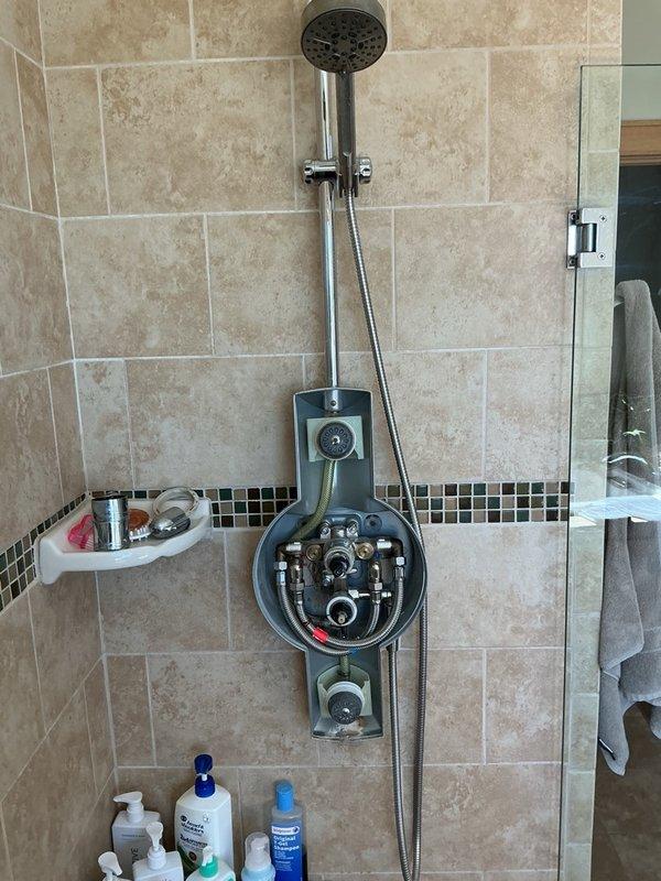 Responded to service call for leaking shower fixture and outdoor spigot. Upon inspection, identified failed shower valve cartridges causing water leakage at the shower assembly. Documented existing conditions with photographs showing the shower fixture with exposed valve mechanisms and plumbing connections. Assessed the shower system which included a handheld showerhead with flexible hose and mounting bracket, along with the associated valve assembly requiring cartridge replacement. Provided estimate for necessary cartridge replacements to resolve the leaking conditions at both the interior shower fixture and exterior spigot.