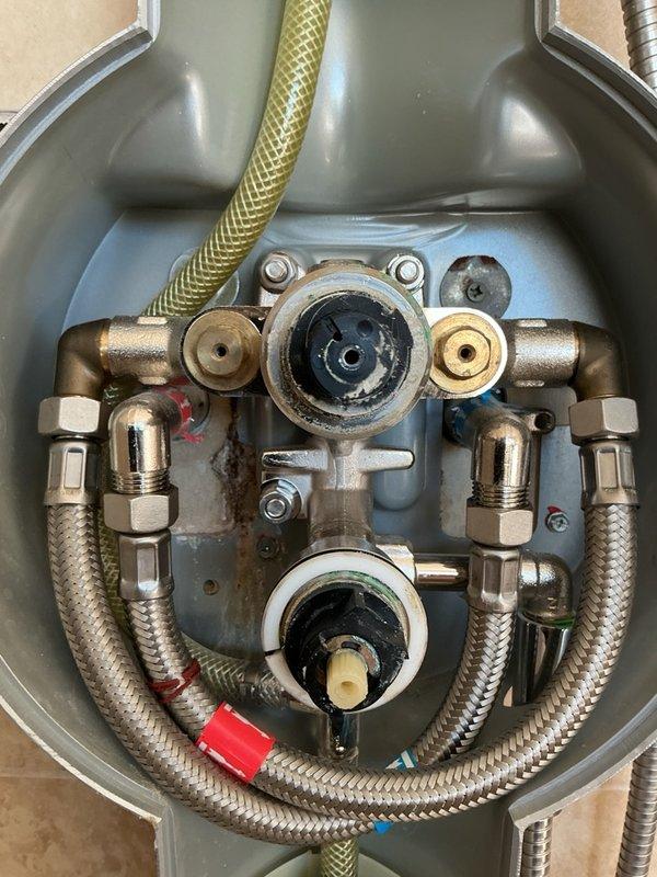 Responded to service call for leaking shower fixture and outdoor spigot. Upon inspection, identified failed shower valve cartridges causing water leakage at the shower assembly. Documented existing conditions with photographs showing the shower fixture with exposed valve mechanisms and plumbing connections. Assessed the shower system which included a handheld showerhead with flexible hose and mounting bracket, along with the associated valve assembly requiring cartridge replacement. Provided estimate for necessary cartridge replacements to resolve the leaking conditions at both the interior shower fixture and exterior spigot.
