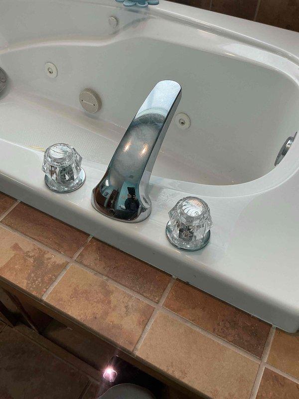 Responded to a service call for a leaking three-hole faucet assembly mounted on a jetted bathtub deck. Upon diagnostic inspection, identified that the cold side cartridge was leaking when water was turned on. Removed the defective cold side cartridge and installed a manufacturer-approved replacement cartridge compatible with standard brands including Moen and Delta. Following installation, tested the faucet assembly to verify proper operation of both hot and cold water handles. Confirmed no leaks were present at the cartridge seat or surrounding connections. The chrome faucet with clear acrylic handles is now functioning correctly with full water flow control and no active leaks.