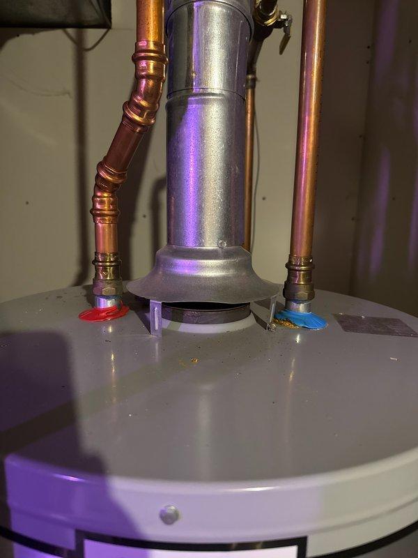 Responded to service call for 3-year-old gas water heater exhibiting corrosion on top of unit and melted plastic caps from previous backdrafting issue. Inspected A.O. Smith ProLine water heater and confirmed cosmetic damage to plastic caps with evidence of prior negative pressure problems. Cleaned corrosion residue from backdrafting on top of tank and replaced nine melted plastic caps. Advised that plastic caps serve cosmetic purposes only and verified that HVAC contractor had previously addressed and resolved the negative pressure issue causing the backdrafting condition. Unit operational with proper venting function restored.