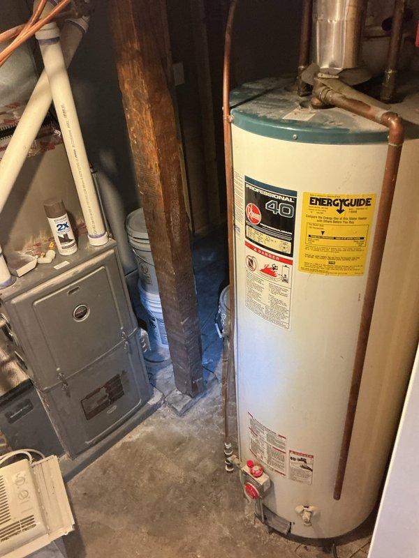 Responded to service call for water heater venting issue in residential basement. Upon inspection, identified improper back-venting condition on natural gas standard atmospheric vent water heater causing drafting problems. Corrected venting configuration to ensure proper draft and safe exhaust of combustion gases. Verified unit operation and proper venting performance upon completion. Documented existing 40-gallon tank water heater installation with standard copper supply line connections and expansion tank present. All work performed in accordance with current plumbing and mechanical codes for natural gas appliance venting requirements.