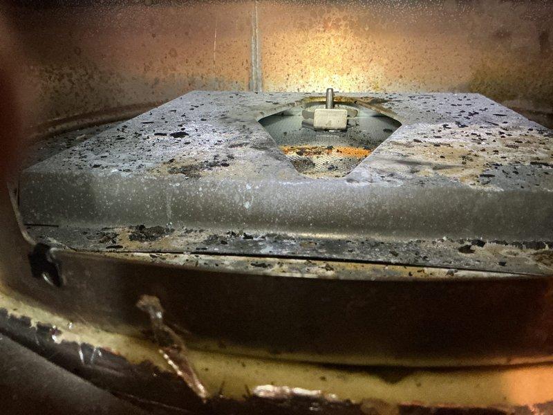 Responded to service call for water heater that would not stay lit and was not producing hot water. Following initial inspection attempt, performed thorough diagnostic by removing burner assembly for detailed examination. Discovered failed flue damper assembly with shattered glass spacer component, causing damper to close and restrict oxygen flow to burner flames. Identified unit as less than two years old and likely covered under manufacturer warranty. Documented failed flue damper assembly condition with photos and recommended warranty replacement of defective component to restore proper combustion air flow and water heater operation.