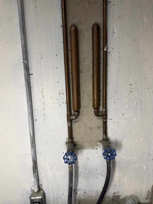 Completed comprehensive plumbing inspection for recurring maintenance service. Inspected ceiling-mounted Moen fixture showing age-related wear, discoloration, and dirt accumulation on metallic components. Evaluated copper pipe risers with U-shaped loops and shut-off valves featuring blue spoke-style handles; noted oxidized patina consistent with system age. Documented conditions and sent estimates for recommended repairs or replacements.