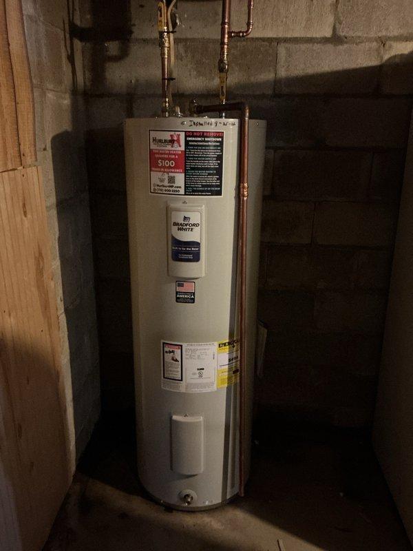Responded to emergency water heater failure caused by tank leak that allowed water to contact electrical connections, creating a sparking hazard. Upon inspection, confirmed the existing water heater had failed due to bottom tank corrosion and active leaking, making repair unsafe and unfeasible. Removed and properly disposed of the failed unit. Installed new Bradford White residential tanked water heater in basement location against concrete block wall. Connected copper supply lines to top of unit with brass fittings and shut-off valves. Verified all plumbing connections for proper seal and tested system operation. Installation completed per manufacturer specifications and local plumbing codes.