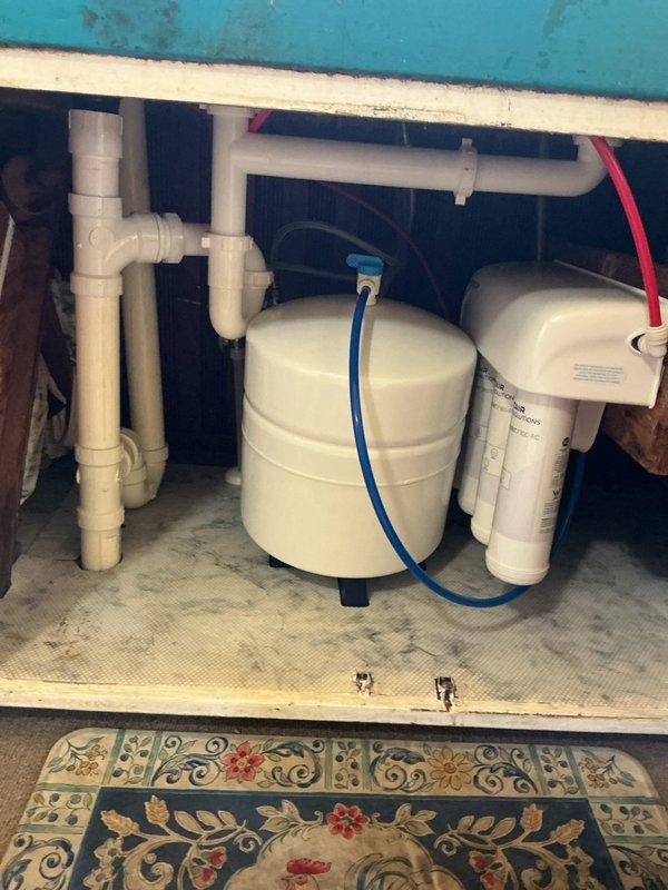Removed and replaced failing well pressure tank with new WX 202 20-gallon pressure tank assembly in basement utility area. Installed new tank utilizing existing tee assembly and connections to maintain proper water flow and prevent pump motor burnout. Additionally installed spin down sediment filter and reverse osmosis system under kitchen sink, connecting filtration components with appropriate tubing and fittings. All copper piping, brass fittings, and pressure gauges verified for proper operation. System tested and confirmed operational per original estimate specifications.