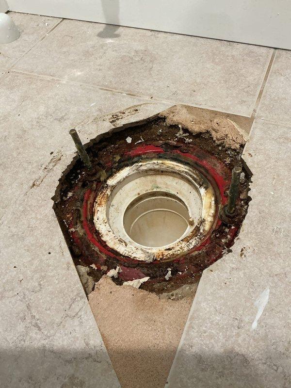 Responded to a callback for water leaking from beneath bathroom tile into floor drain following toilet replacement. Upon arrival, verified active leak concern and removed toilet to inspect installation. Discovered three to four horned wax rings improperly stacked together at the base, with toilet flange positioned below the finished tile floor level—a condition preventing proper seal formation.

Removed all existing horned wax rings and prepared flange surface. Formed a new large wax ring to compensate for the recessed flange position and installed it to create an adequate seal between the toilet base and drainage system. Applied additional wax to seal visible joints and potential leak paths around the flange connection. Reinstalled toilet, ensuring proper compression of wax ring and secure mounting to floor. Advised monitoring for any continued leakage and to contact for follow-up service if issue persists.