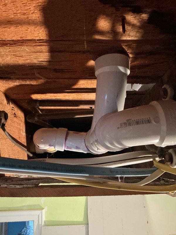 Responded to customer complaint of water backing up into shower when washing machine drains. Inspected the laundry area with stacked washer-dryer unit and examined exposed plumbing beneath the floor joists. Identified inadequate drainage piping configuration connecting the washing machine discharge to the main drain line. Documented existing PVC pipe layout and determined that the current piping system requires reconfiguration to prevent cross-drainage issues. Provided estimate for repiping the shower and washer drain lines to establish proper drainage and eliminate backup conditions.