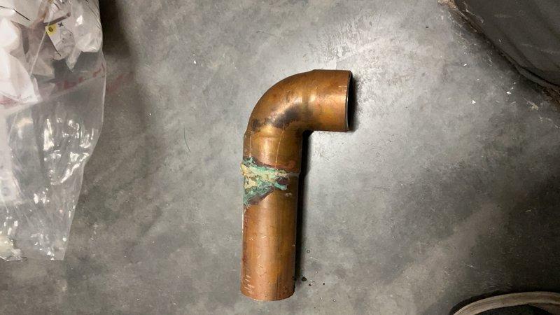 Responded to commercial water leak in main mechanical room serving three large water heaters. Upon arrival, found active leak on 1.5"-2" copper main line with insulation compromised and standing water throughout the floor area. Facility was closed at time of service, requiring coordination for building access. Identified corroded section of copper piping as source of leak, with visible oxidation and deterioration at failure point. Isolated affected section, cut out damaged copper pipe, and installed new copper section with proper fittings and connections. Tested system for proper operation and verified leak was eliminated. Noted early-stage mold growth present due to prolonged moisture exposure in mechanical room.
