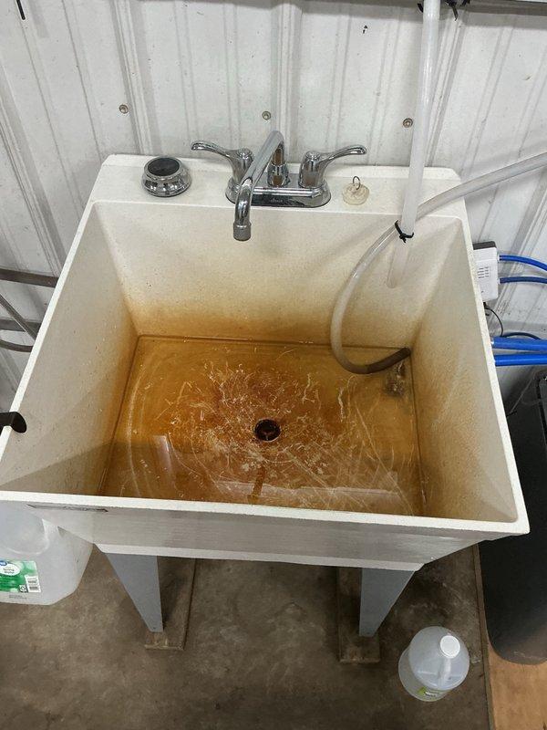 Responded to a clogged drain issue affecting a washtub sink and stainless steel dog bathing tub in a shed utility area. Upon inspection, found the sink basin full of standing water mixed with dog wash residue. Located the obstruction at the tee fitting below the sink drain line. Removed the clog, cleared all debris from the drain assembly, and performed thorough flushing with water to verify proper drainage and flow restoration. Both fixtures returned to normal operation with no further backup or slow drainage issues.