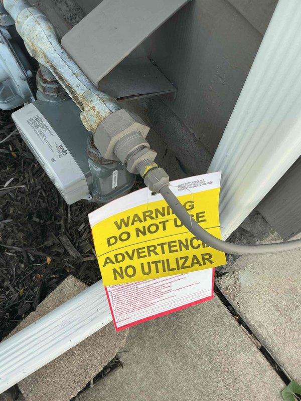Responded to gas leak emergency previously identified and tagged by utility company on exterior gas main line. Documented hazardous condition with warning tags visible on weathered, corroded gas piping at meter location. No interior gas odor detected during inspection, confirming leak isolated to exterior system. Coordinated scheduling with licensed plumber for repair work to address utility-marked leak location.
