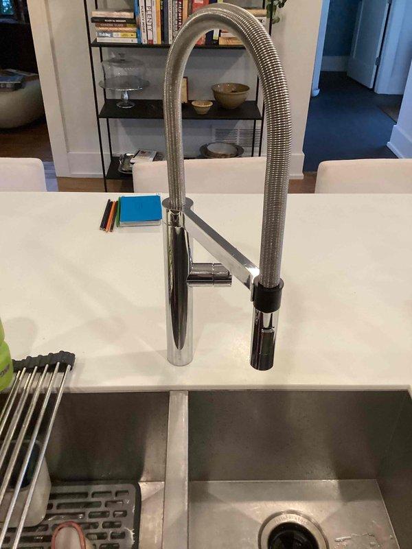 Returned to property to complete faucet repair with correct replacement parts. Successfully replaced the kitchen faucet sprayer assembly on the professional-style pull-down faucet with chrome finish and coil spring design. Unit is now fully operational with proper spray head functionality restored.