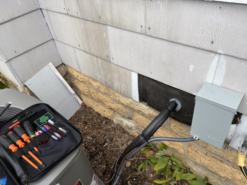 Completed code correction callback for AC installation to address inspector findings per SPS 321.24 requirements. Pumped down refrigerant, disconnected and removed line set and exterior disconnect box. Reinstalled slate siding that had been previously removed during initial installation to restore permanent weather-resistant finish on exterior wall. Drilled new penetrations for line set and disconnect, ensuring proper placement through restored siding. Reinstalled line set and disconnect box in code-compliant configuration. Sealed all exterior penetrations with approved caulking and applied spray foam insulation to interior penetrations to prevent water and pest intrusion, properly sealing water resistive barrier as required by code.