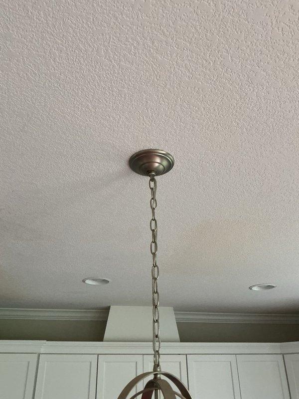 Responded to report of water leak from upstairs bathroom area penetrating ceiling and affecting kitchen light fixture below. Systematically tested all upstairs plumbing fixtures including four vanity sinks, two showers, two toilets, and laundry connections by running water down each drain for extended periods. Inspected floor areas around toilets and beneath vanities for standing water or active leaks. Unable to replicate the reported leak condition during service visit. Customer indicated that shower curtain may not have been properly positioned inside tub during recent use, potentially allowing water to escape onto floor and seep through to ceiling below, which is consistent with the intermittent nature of the leak and lack of visible plumbing defects found during inspection.