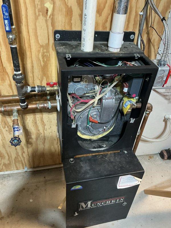 Responded to no heat call on 2007 Munchkin boiler serving radiant in-floor heating system. Upon arrival, found system experiencing recurring low pressure issues and short cycling. Diagnostic testing revealed failed thermostat, compromised ignitor and flame sensor causing cycling issues. Jumped thermostat wires to isolate and confirm thermostat failure. Further inspection identified significant heat exchanger deterioration - unit showing signs of plugging, burnout, and active water leakage through heat exchanger. System pressure loss traced to failed heat exchanger. Documented gauge readings and internal component condition with photos. Advised that heat exchanger failure on this 17-year-old unit represents unsafe operating condition with continued water loss and no viable repair option. Provided temporary restoration by replacing thermostat to restore immediate operation, but strongly recommended complete boiler replacement due to failed heat exchanger presenting safety hazard and immi