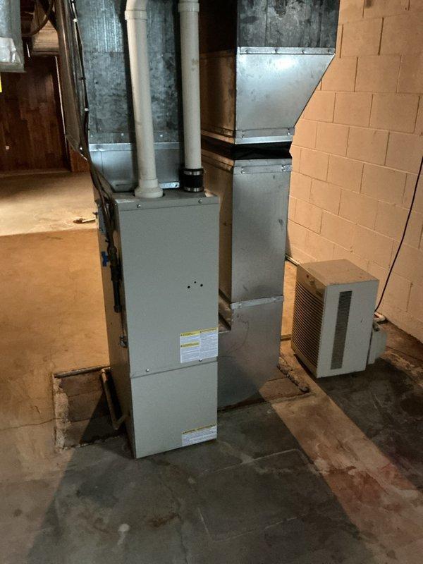 Performed inspection of 8-year-old tanked water heater in response to venting concerns. Upon examination, identified improper venting configuration with back-pitched vent pipe, which violates code requirements and creates potential for condensate accumulation and exhaust gas spillage. Documented existing conditions with photographs showing water heater installation alongside HVAC system in basement mechanical room. Verified water heater connections including gas supply lines with red valve handles and blue water connections at base of unit. Assessed overall system condition and surrounding mechanical equipment including furnace with white PVC intake/exhaust vents and metal ductwork. Provided estimates for new water heater replacement to address venting deficiencies and ensure proper code-compliant installation.