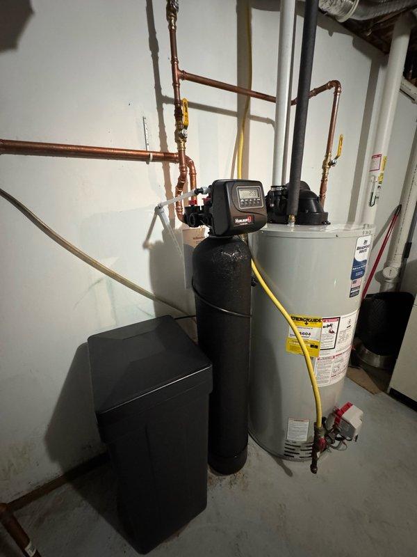 Upgraded residential water system by removing existing 202 model 20-gallon pressure tank and installing new 203 model 30-gallon pressure tank with new gooseneck fitting. Reconfigured copper piping connections to accommodate larger tank capacity and ensured proper integration with existing water heater and treatment system. All connections tested and system restored to full operation.