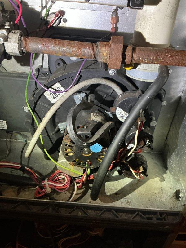 Responded to no heat call on 18-year-old furnace system. Upon arrival, confirmed blower fan was activating but furnace failed to ignite. Performed diagnostic inspection and identified failed draft inducer motor as root cause of system failure. Draft motor showed no operation when heating cycle was called for, preventing proper venting and safety lockout of ignition sequence. 

Documented existing system conditions including significant corrosion on gas piping and general age-related wear throughout unit. Explained findings and repair options to property owner via phone communication, as this was a rental property with owner off-site. Given the age of the equipment at 18 years and the cost of draft motor replacement, recommended comfort advisor consultation to evaluate repair versus replacement options. Provided photographic documentation of failed component and overall system condition for owner review and decision-making purposes.