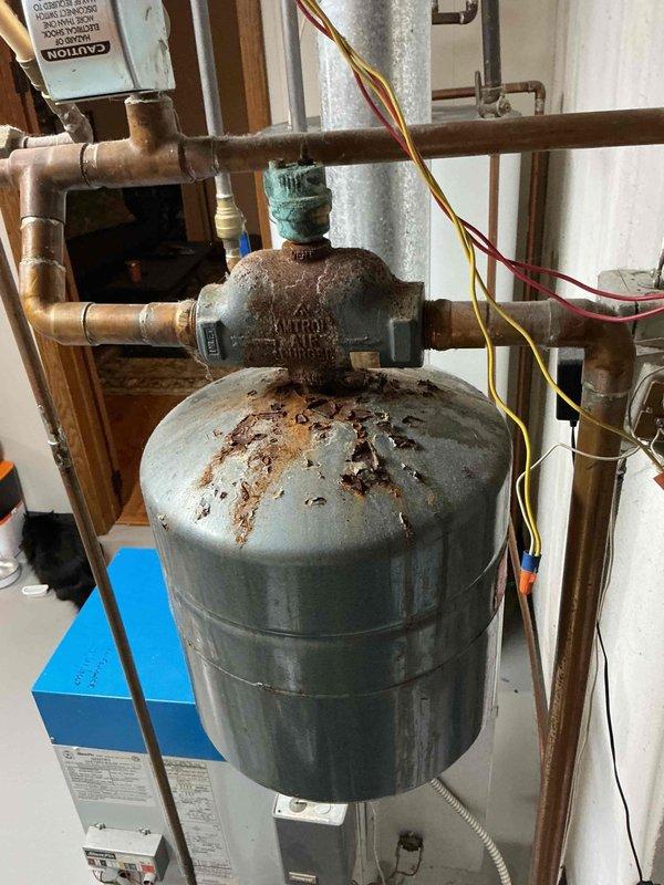 Responded to service call for boiler overheating issue. Upon inspection, discovered the boiler control valve was stuck in the open position, causing continuous heating and inability to maintain proper temperature regulation. Identified multiple leaks in the system piping and connections, with visible corrosion on expansion tank and aged copper piping assembly. Documented equipment condition with photos showing rust accumulation on tank surfaces and deteriorated plumbing components. Provided customer with detailed repair options and submitted written estimate for necessary repairs to address control valve replacement and leak remediation.