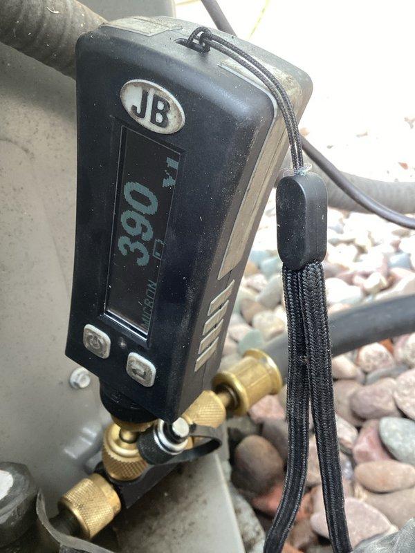 Responded to no cooling complaint and found compressor terminal blown off. Replaced failed compressor under parts warranty, ensuring proper refrigerant recovery and system evacuation prior to installation. Cleaned condenser coil thoroughly and removed oil stains from condenser unit exterior. Performed system startup, verified proper operating pressures at 390 PSI as shown on digital gauge, and confirmed adequate cooling performance. Unit restored to full operational status.
