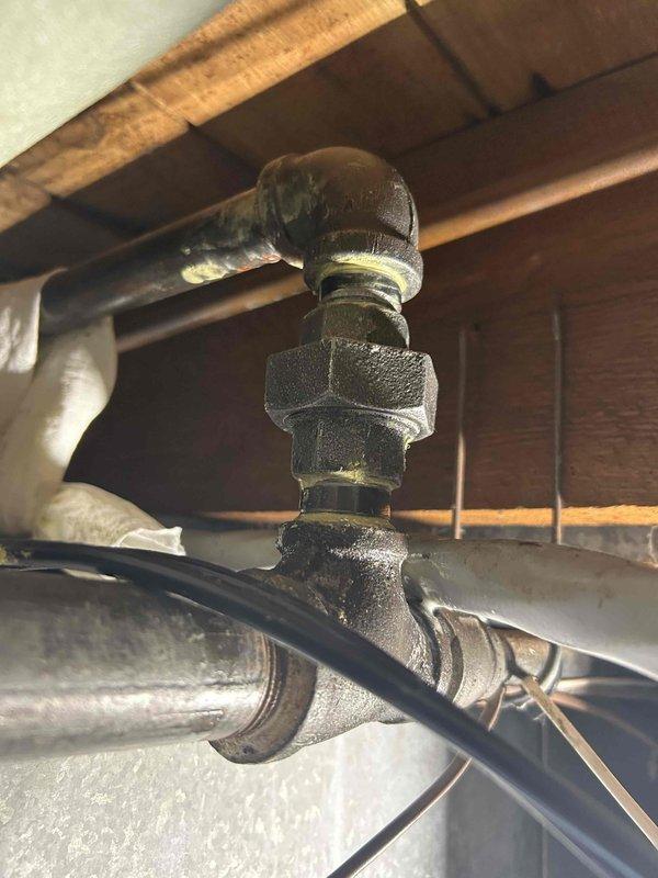 Responded to gas leak identified during home efficiency testing. Located active leak at three-quarter inch 90-degree elbow fitting on gas line supplying garage and dryer above furnace area. Due to configuration and accessibility constraints, determined optimal repair method was to cut existing nipple and re-thread pipe with union connection rather than disassembling entire gas line assembly. Obtained homeowner approval and proceeded with repair. Cut affected nipple, re-threaded pipe, and installed union fitting. Performed comprehensive leak check on repaired connection and surrounding gas line components. Confirmed all connections holding properly with no detectable leaks. System restored to safe operating condition.