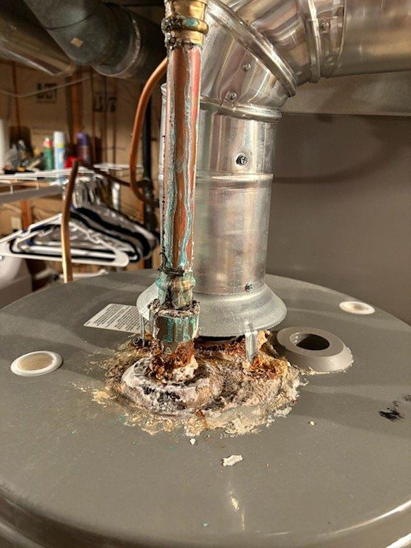 Responded to a leak at the top of a 2-year-old Rheem water heater. Upon inspection, identified a failed solder joint at the 90-degree elbow above the unit, which was causing active water leakage and significant corrosion at the connection point. Replaced the defective 90-degree fitting and the water heater shut-off valve to ensure proper seal and prevent future leaks.