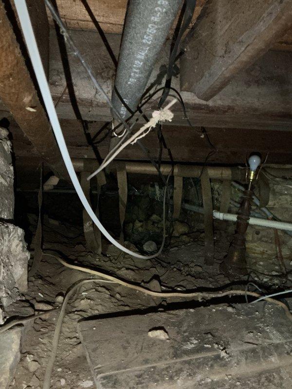 Provided estimate for capping hot and cold water lines in preparation for bathroom demolition in 110-year-old home with galvanized plumbing. Accessed 5-foot crawlspace to assess shower supply lines and documented existing conditions, including aged galvanized piping, stone foundation, and limited workspace beneath wooden floor joists. Customer will schedule service to complete line capping once demolition begins.