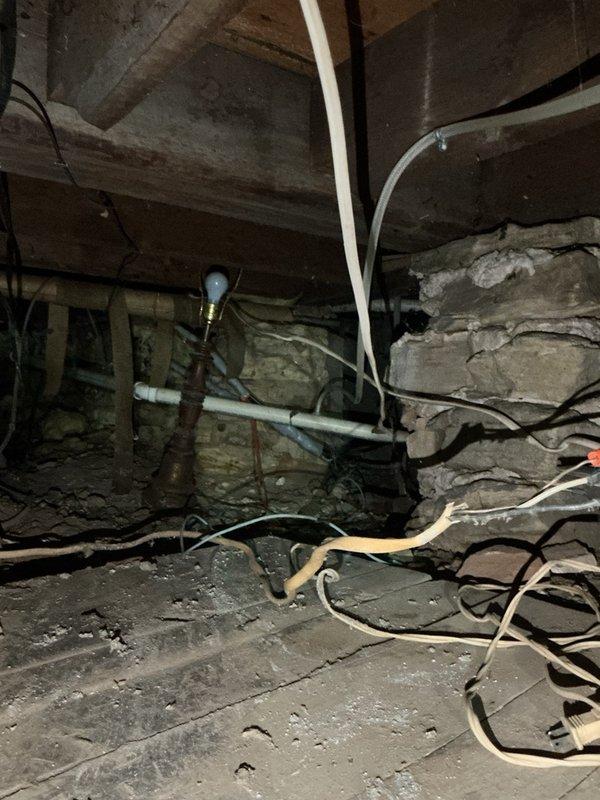Provided estimate for capping hot and cold water lines in preparation for bathroom demolition in 110-year-old home with galvanized plumbing. Accessed 5-foot crawlspace to assess shower supply lines and documented existing conditions, including aged galvanized piping, stone foundation, and limited workspace beneath wooden floor joists. Customer will schedule service to complete line capping once demolition begins.