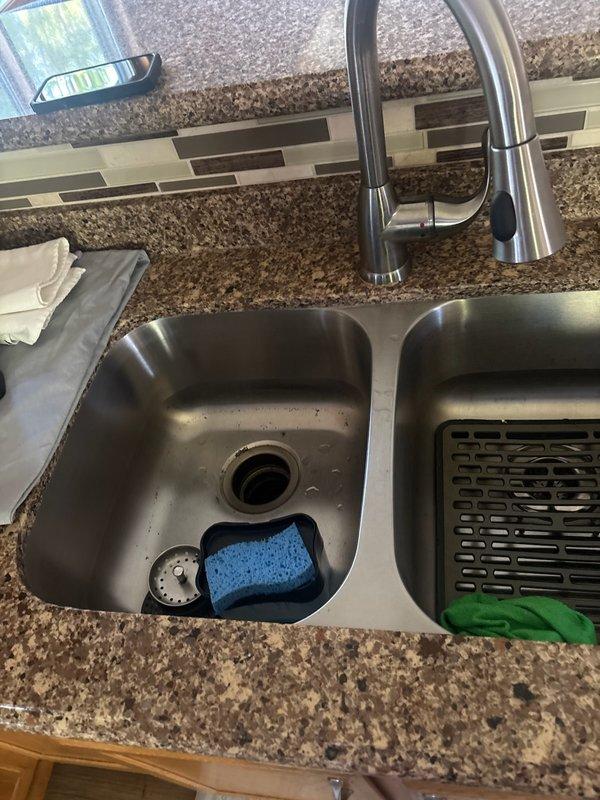 Responded to service call for non-functioning garbage disposal with drainage issues. Upon inspection, determined the existing disposal unit was frozen and completely plugged, preventing proper operation and water flow through the sink drain. Removed the failed disposal unit from the mounting assembly beneath the double-basin kitchen sink and disconnected all plumbing connections. Installed new garbage disposal unit, reconnected to existing drain lines and electrical supply, and tested operation to ensure proper functionality and drainage. System restored to full working order.