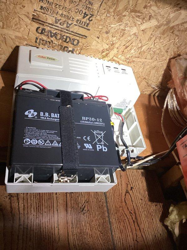 Responded to alarm activation reported as sump pump issue. Upon inspection, determined alarm was originating from a CyberPower battery backup unit installed in crawl space, which provides power to the property's security camera system rather than the sump pump. Unit contains dual B.B. Battery BP20-12 sealed lead-acid batteries with proper wiring connections intact. No plumbing or sump pump issues identified. Advised property owner to contact their telecommunications or security camera service provider for alarm diagnostics and resolution of the backup power system alert.