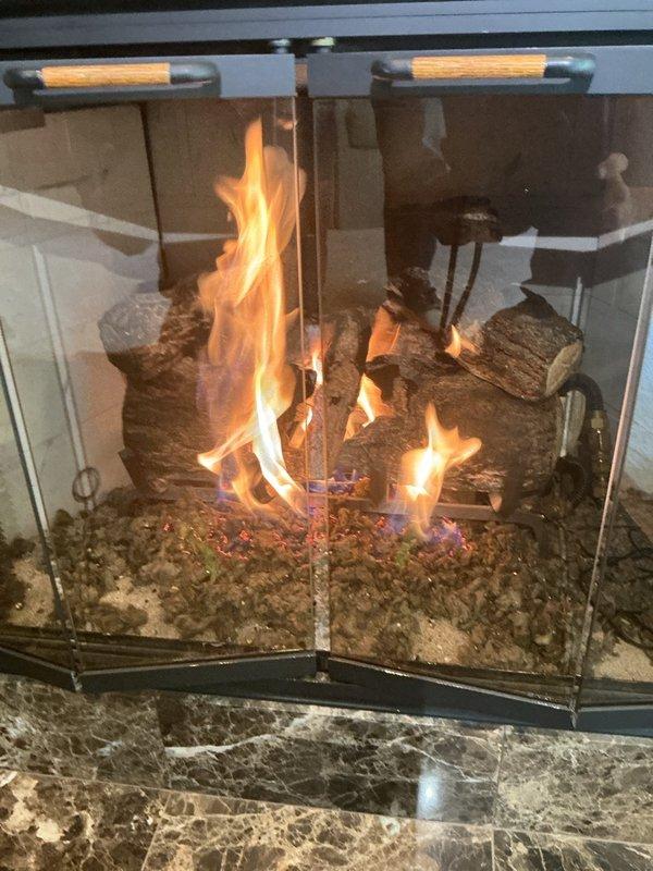 Responded to service call for two gas fireplace units with operational issues. Upon arrival, found upstairs fireplace with extinguished pilot light. Successfully relit pilot assembly and verified unit ignited immediately with proper flame pattern and continued operation. 

Addressed downstairs fireplace experiencing reported intermittent shutdown after approximately two minutes of runtime. Performed diagnostic inspection of flame sensor, which showed no visible defects or fouling. Replaced remote control batteries as preventive maintenance measure. Conducted extended operational test running unit continuously for twenty minutes with no shutdown occurrences, confirming system stability. Observed heavy soot accumulation and charring on ceramic log set indicating need for future maintenance cleaning. Both fireplace units left in proper working order with stable ignition and sustained operation verified.