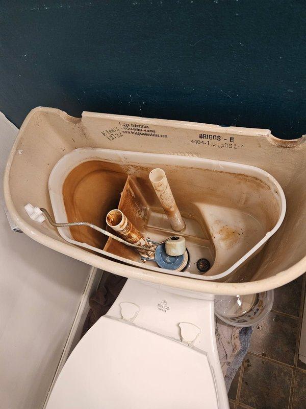 Responded to a toilet malfunction involving multiple component failures. Upon inspection, discovered a continuously running flush mechanism, leaking tank, and severely deteriorated closet flange with completely rusted mounting bolts causing the fixture to wobble. The tank-to-bowl bolts were seized and could not be removed. Due to the extent of deterioration in the low-grade Briggs toilet and compromised flange assembly, performed complete toilet replacement and closet flange repair to restore proper function and ensure secure mounting.