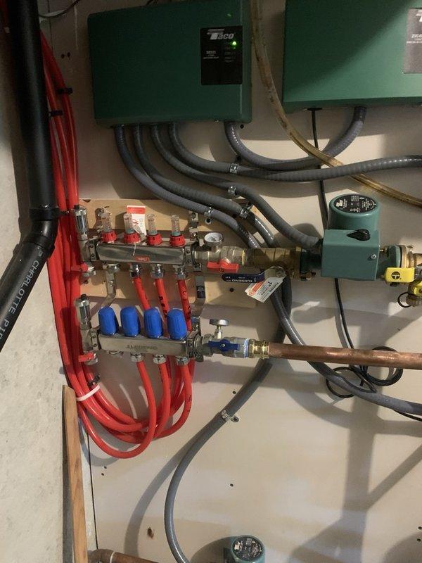 Replaced corroded 3-loop hydronic manifold serving upstairs bathroom zones and leaking pump flange on one heating zone. Cleaned corrosion from affected piping, reconnected all distribution lines to new manifold assembly, and purged air from the system. Set system pressure to 18 psi, replaced thermostat batteries, and cycled all zones to verify proper operation with no leaks detected.