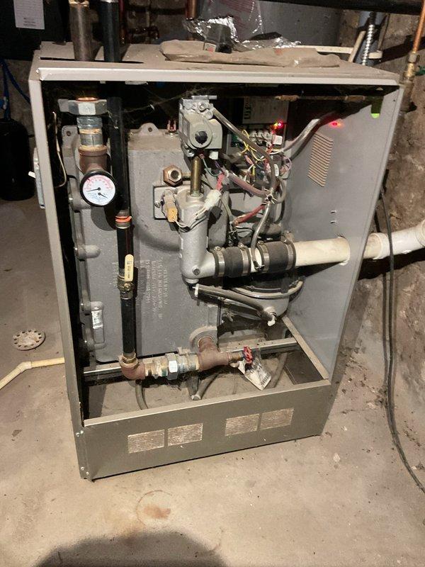 Responded to service call for outdoor central boiler reported as not working. Performed comprehensive system inspection of both the outdoor wood-fired boiler and indoor gas boiler. Verified outdoor wood boiler damper assembly and mechanical components are functioning properly; unable to confirm full operational status without firing unit. Inspected indoor gas boiler, confirmed system appears operational with all visible components, pressure gauge, gas valve assembly, and piping connections in working order. Verified circulating pump was operational during previous heating season per customer report. Primary issue identified relates to underground electrical wire supply to outdoor boiler unit requiring electrical contractor assessment. Provided customer education on system operation and component functions for both heating systems. Documented equipment condition with photographs for insurance claim purposes related to electrical service failure.