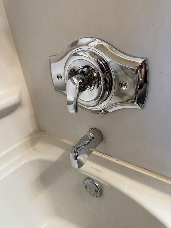 Removed existing shower valve assembly and installed new Moen tub/shower valve with remodel cover plate. Completed installation with better-grade chrome trim kit featuring decorative scalloped trim plate and single-handle control lever. Installed chrome tub spout and standard pop-up drain assembly to complete the fixture upgrade.