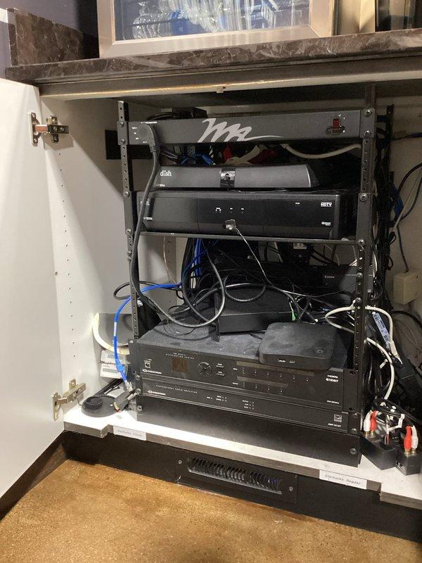 Responded to service call for reported constant screeching noise initially suspected to be from HVAC unit. Upon inspection, determined the noise was not originating from the HVAC system but from a cooling/ventilation fan within an AV equipment cabinet located beneath the countertop. The cabinet houses multiple electronic media components in a rack-mounted configuration with associated networking and power connections. No HVAC repairs were necessary as the unit was operating normally without abnormal sounds.