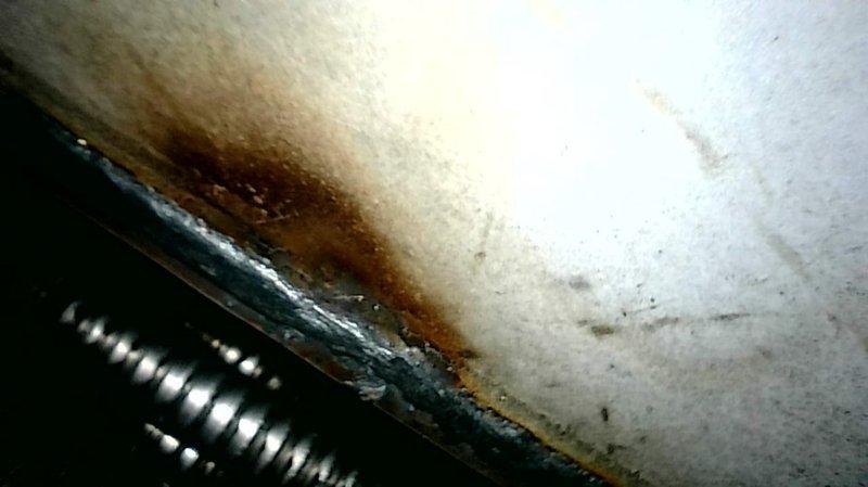 Completed comprehensive furnace tune-up and safety inspection per seasonal maintenance protocol. Performed thorough examination of heat exchanger, which revealed visible signs of corrosion and oxidation on the coil components with rust-colored staining on adjacent surfaces indicating moisture exposure over time. Documented all findings with photographic evidence showing corroded finned heat exchanger sections and discolored drain pan with rust accumulation around drain components. Recommended annual furnace maintenance to monitor heat exchanger integrity and prevent potential safety hazards from continued deterioration.