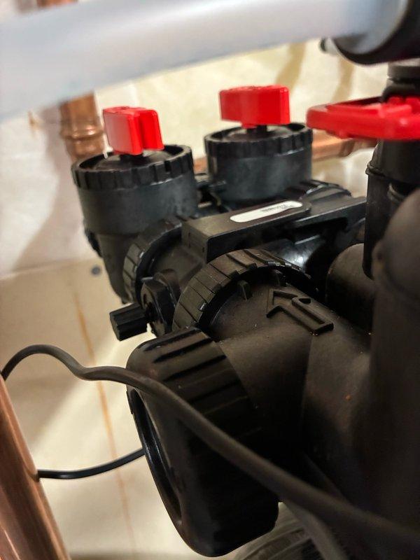 Installed a bypass assembly with integrated bleeder valve on the hydronic heating system manifold. The installation included two red-handled ball valves mounted to black plastic manifold bodies with copper piping connections, along with circulation pump components to allow for proper system maintenance and air purging capabilities.