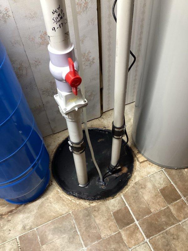 Responded to service call for non-operational sump pump and sewage ejector system. Upon inspection, determined that the sewage ejector pump had failed despite being a relatively recent installation. Replaced the defective sewage ejector pump under manufacturer warranty. Installation included proper mounting of two white PVC discharge pipes with rubber couplings through the floor penetration, secured with a black rubber boot seal. Installed red shut-off valve and control box on pipe assembly for system operation and maintenance access. Tested system functionality and verified proper pump operation and discharge flow.