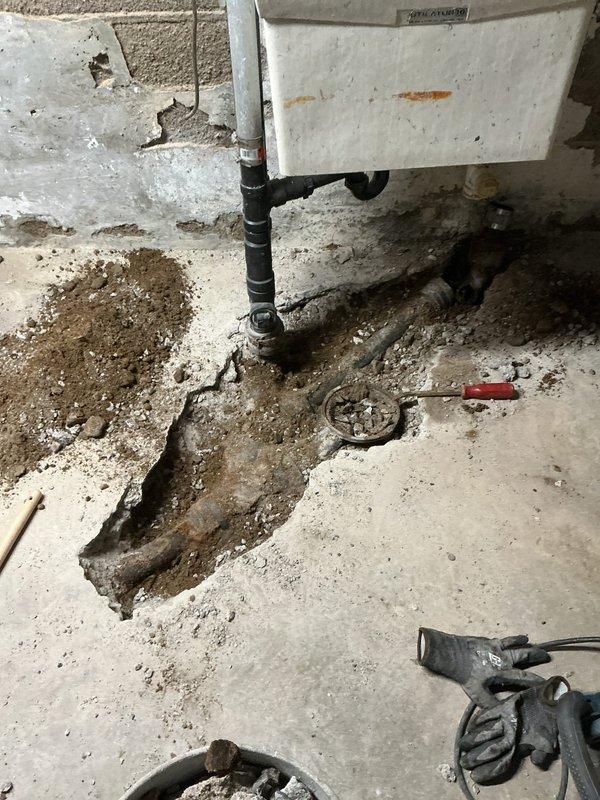 Completed floor drain replacement requiring extensive concrete removal and underground piping renovation. Broke open concrete floor to expose deteriorated cast iron drain piping serving the laundry, kitchen, and floor drain systems. Removed and replaced the first five feet of compromised cast iron piping with new PVC piping, connecting back to existing branch drain lines. Installed new PVC floor drain assembly to code specifications. Properly bedded all new piping with appropriate aggregate material to ensure stable support and prevent future settling. Backfilled excavated area with compacted fill material. Poured and finished new concrete to restore floor surface to original grade. Conducted comprehensive testing of all drain connections to verify proper flow and operation. All systems tested leak-free with adequate drainage performance confirmed prior to completion.