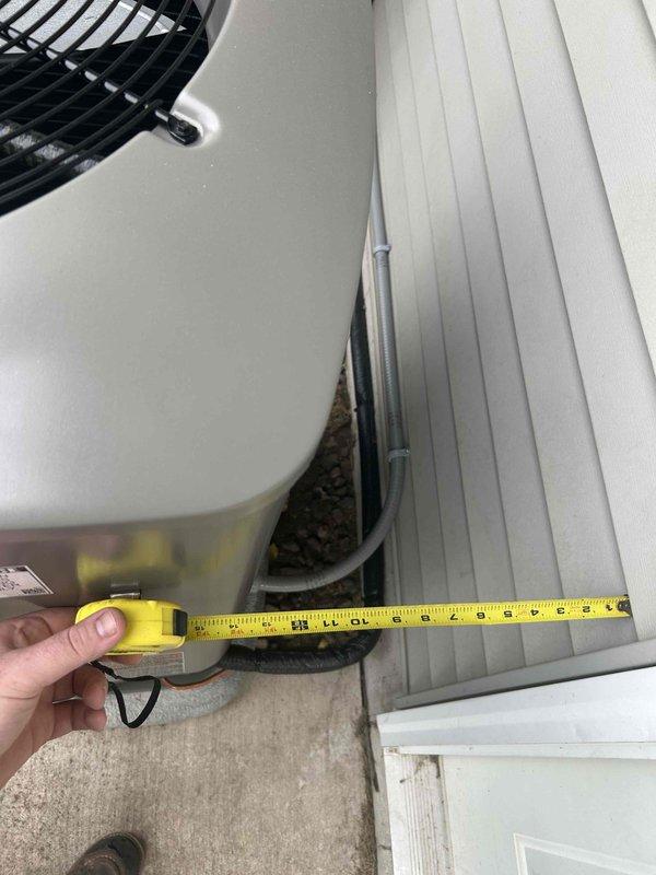 Responded to install callback for recently installed outdoor HVAC system that was positioned too close to garage door entrance, with condensing unit and equipment pad partially obstructing concrete walkway. Assessed clearances and measured distances between unit, house siding, and garage door swing path. Coordinated with install crew to relocate condensing unit and equipment pad approximately 12-18 inches closer to house foundation and off concrete entrance area to resolve door clearance issue and restore full access to garage. Verified proper clearances maintained for equipment serviceability and airflow requirements. Documented final positioning with measurements and photographs showing adequate spacing from structure and unobstructed garage access.